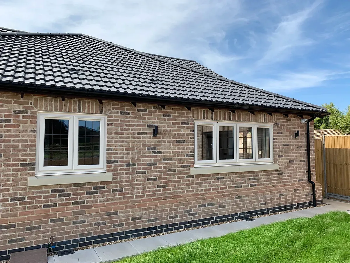 A brick house with white windows and a black roof.