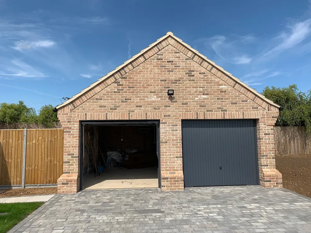 A brick garage with two garage doors and a driveway.