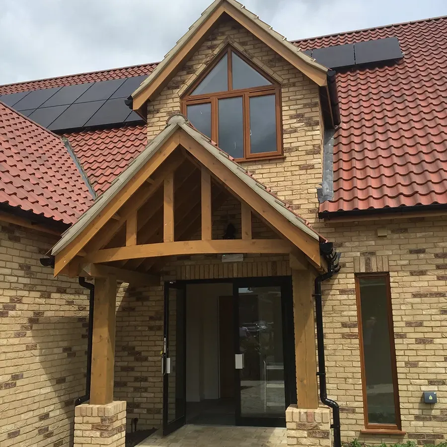 A brick house with a red tile roof and a wooden porch