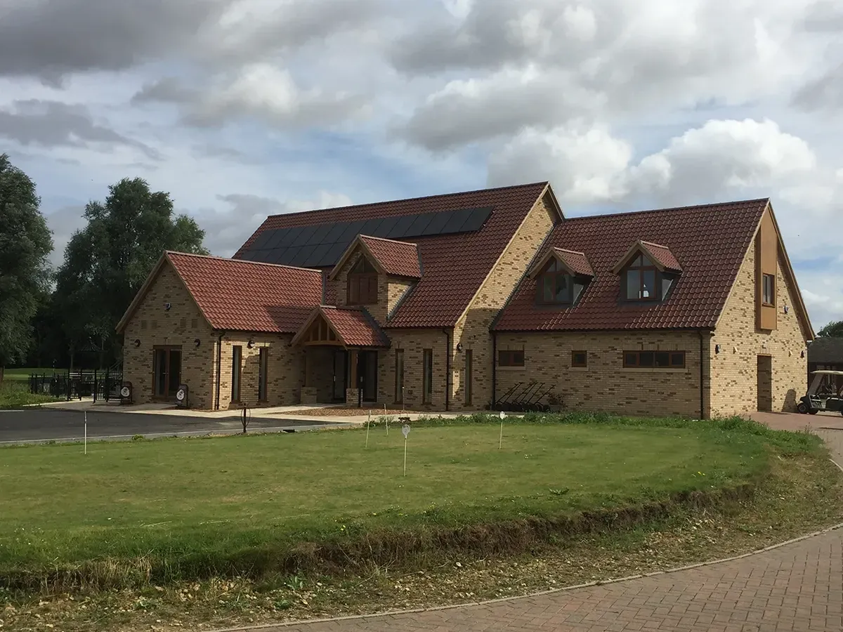 A large brick house with a red tiled roof and solar panels on the roof.