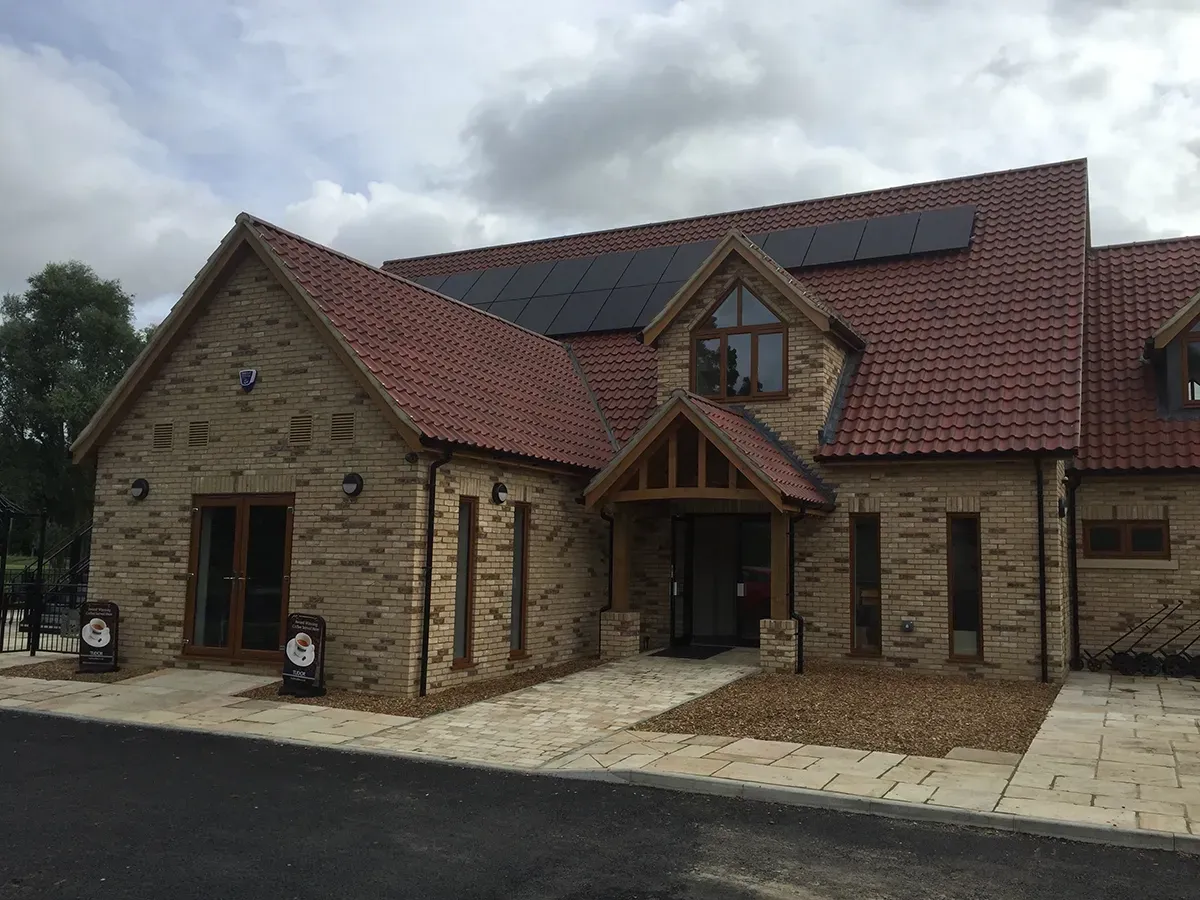 A large brick building with a red roof and solar panels on the roof.