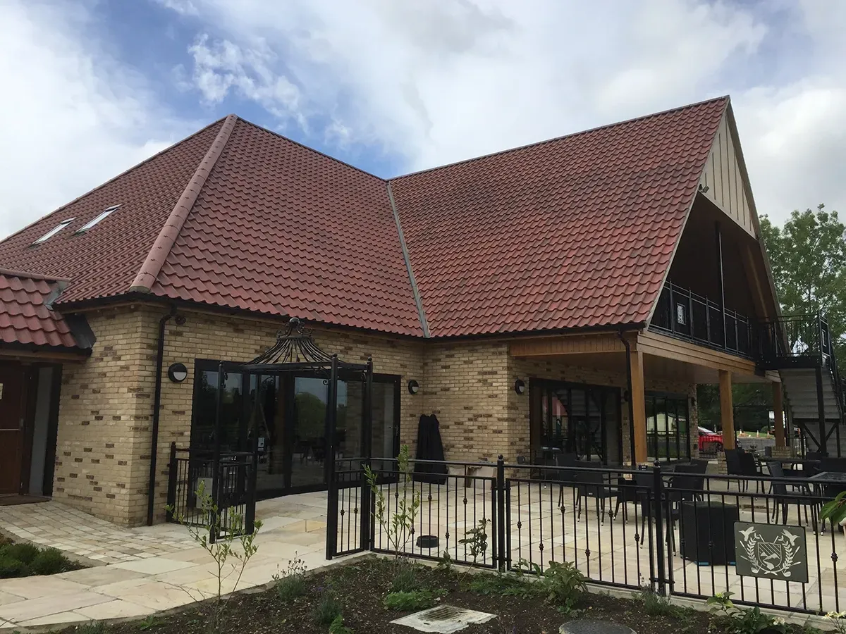 A large brick building with a red tiled roof and a patio.