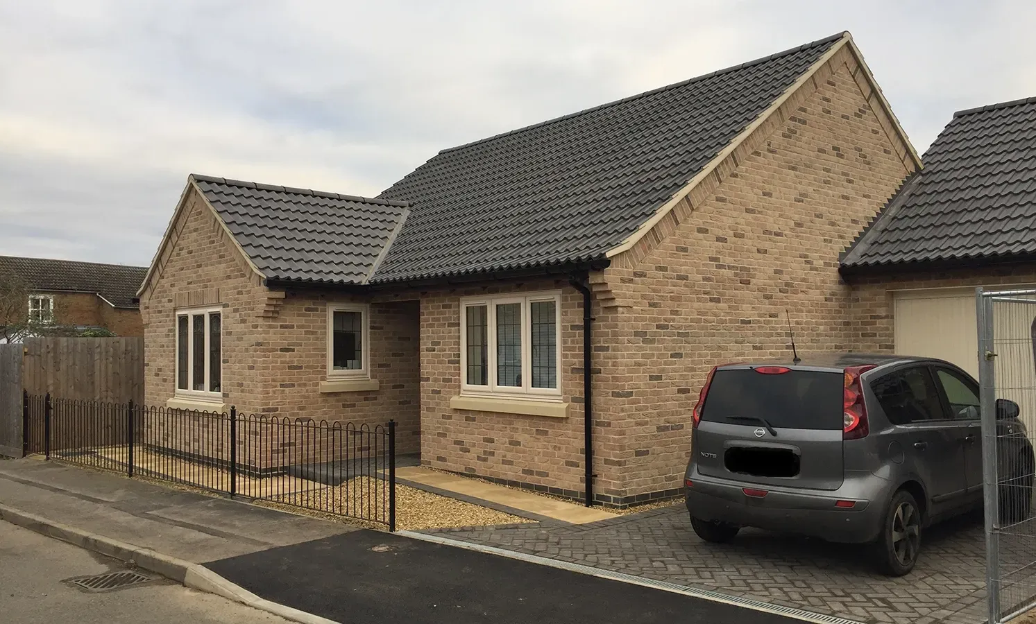 A car is parked in front of a brick house.