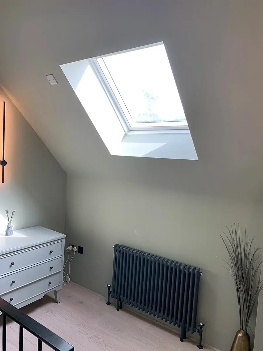 A bedroom with a skylight and a radiator.