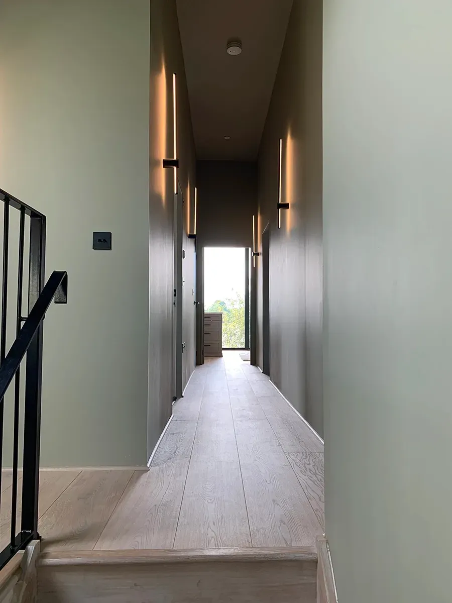 A long hallway with stairs leading up to the second floor of a house.