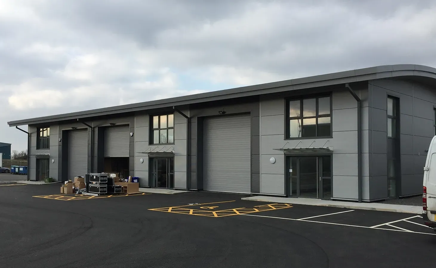 A white van is parked in front of a large building