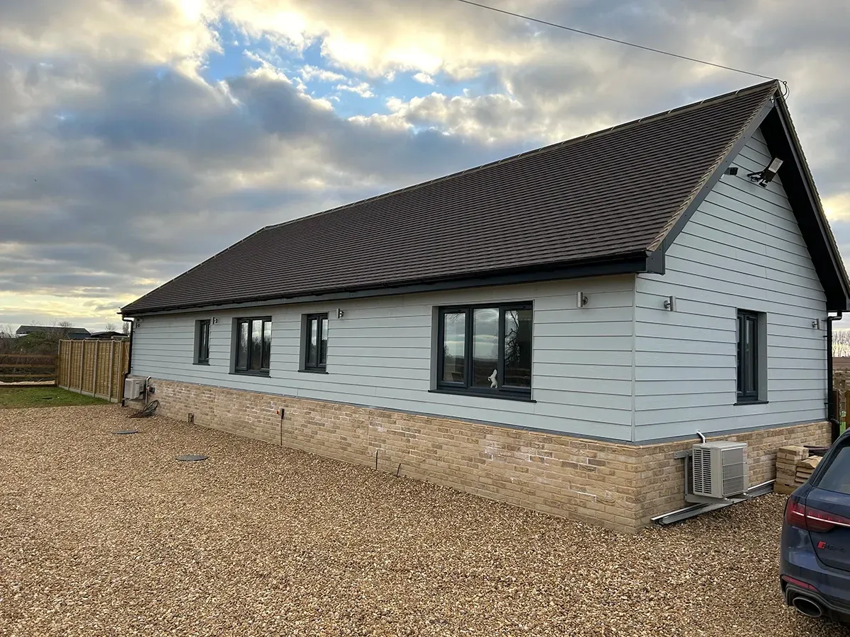 A white house with a brown roof and a car parked in front of it.