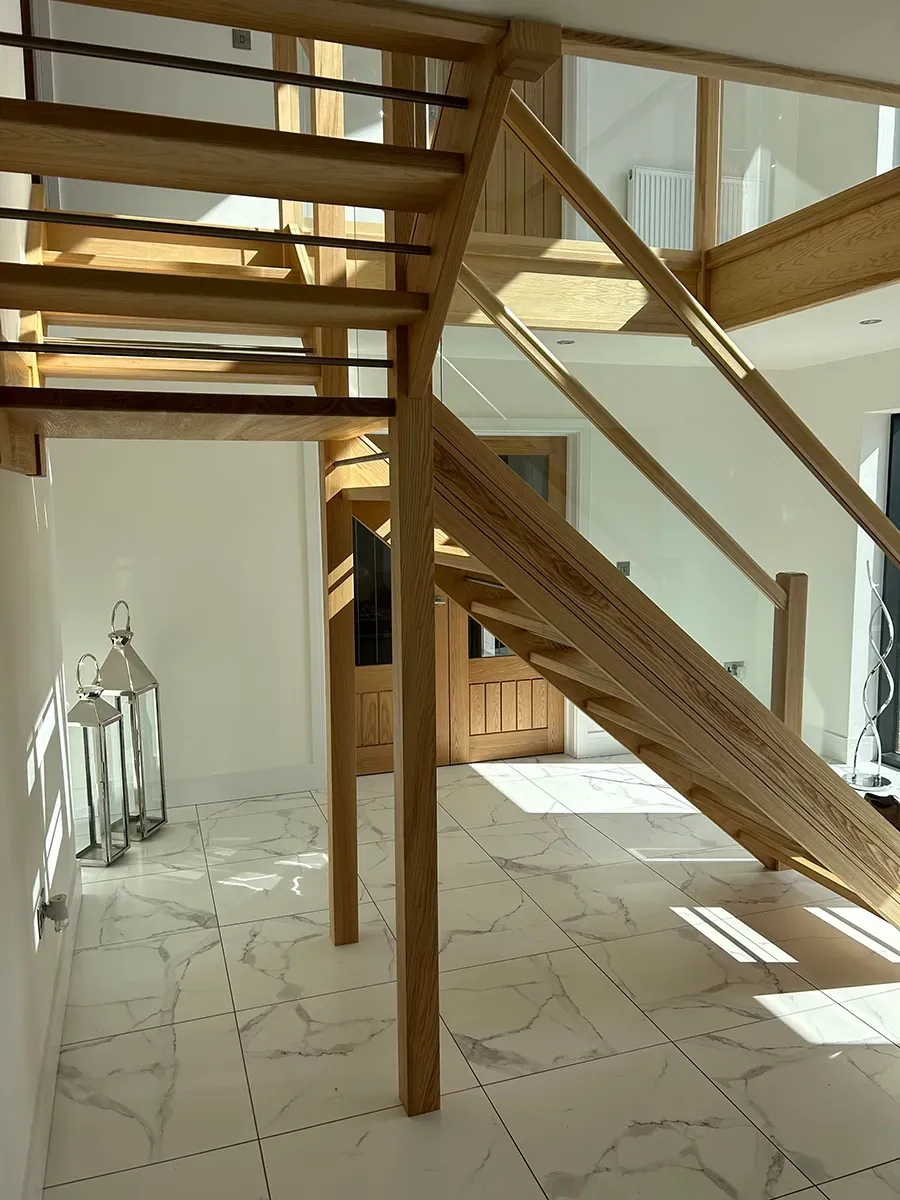 A wooden staircase with a glass railing in a hallway.