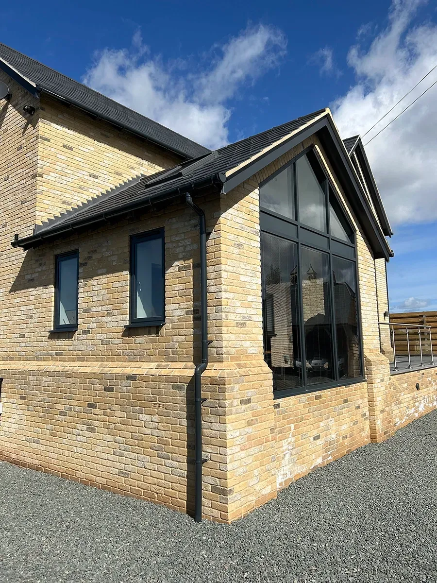 A large brick house with a lot of windows and a blue sky in the background.