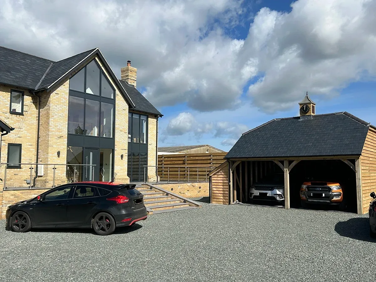 A car is parked in front of a house next to a garage.