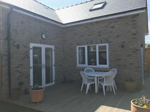 A patio with a table and chairs in front of a brick house.
