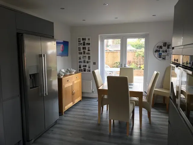 A kitchen with a table and chairs and a refrigerator.