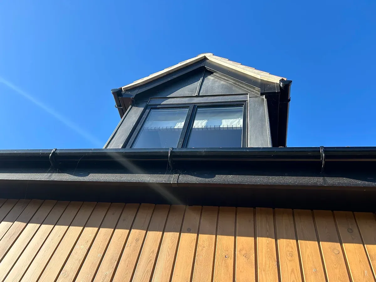 Looking up at the roof of a house with a blue sky in the background.