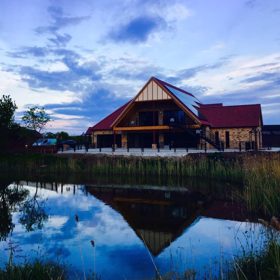 A house with a red roof is reflected in a pond