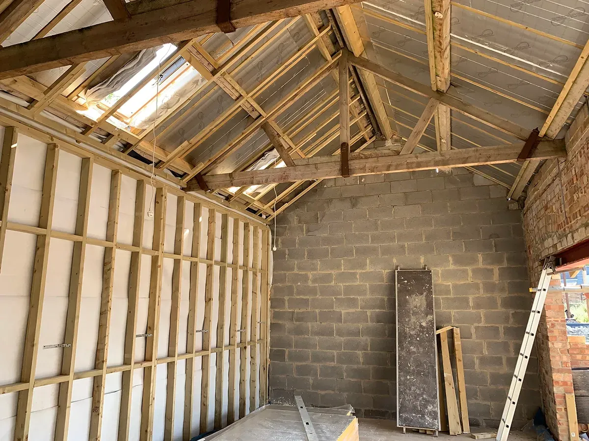 The inside of a building under construction with wooden beams and a ladder.