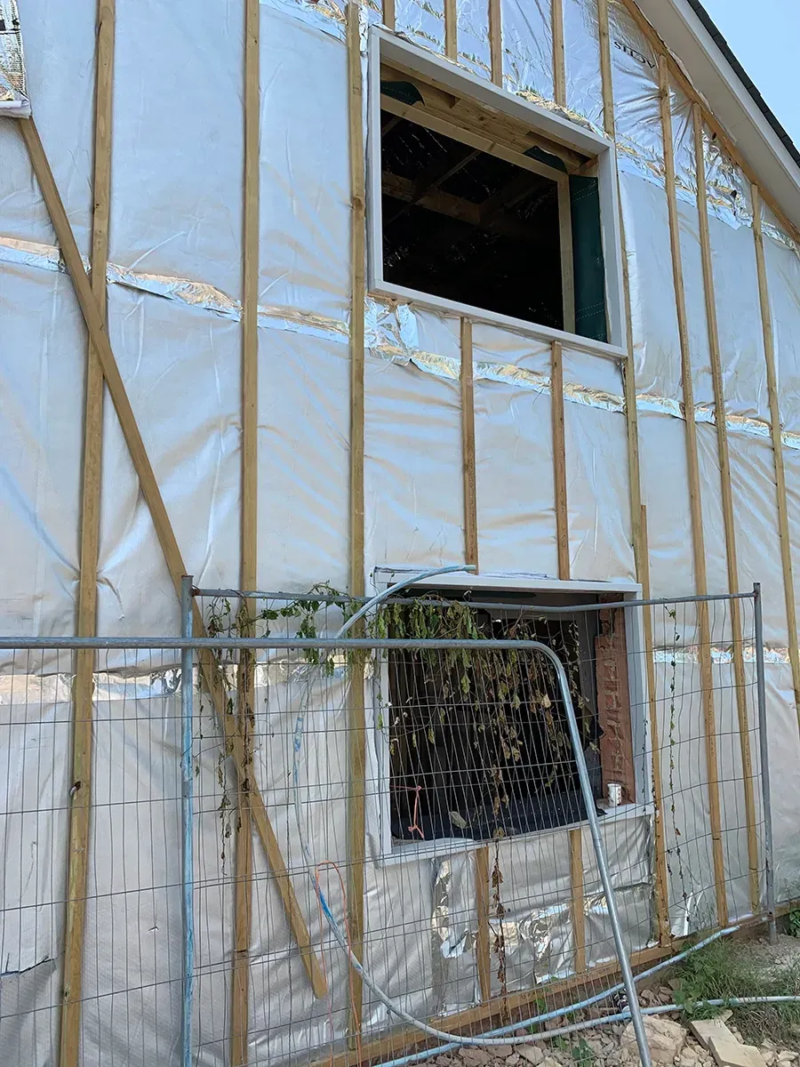 A building with a window and a fence around it is being built.