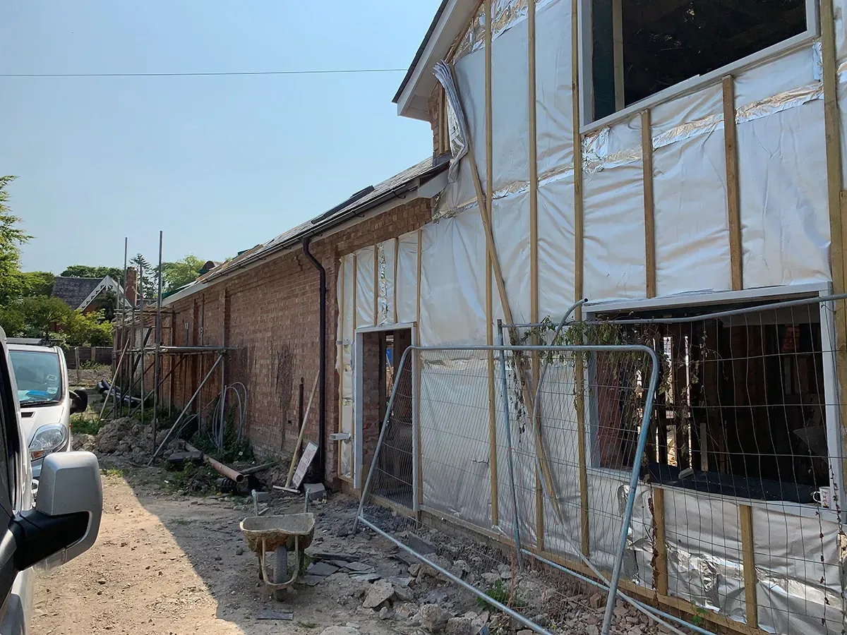 A wheelbarrow is parked in front of a building under construction.