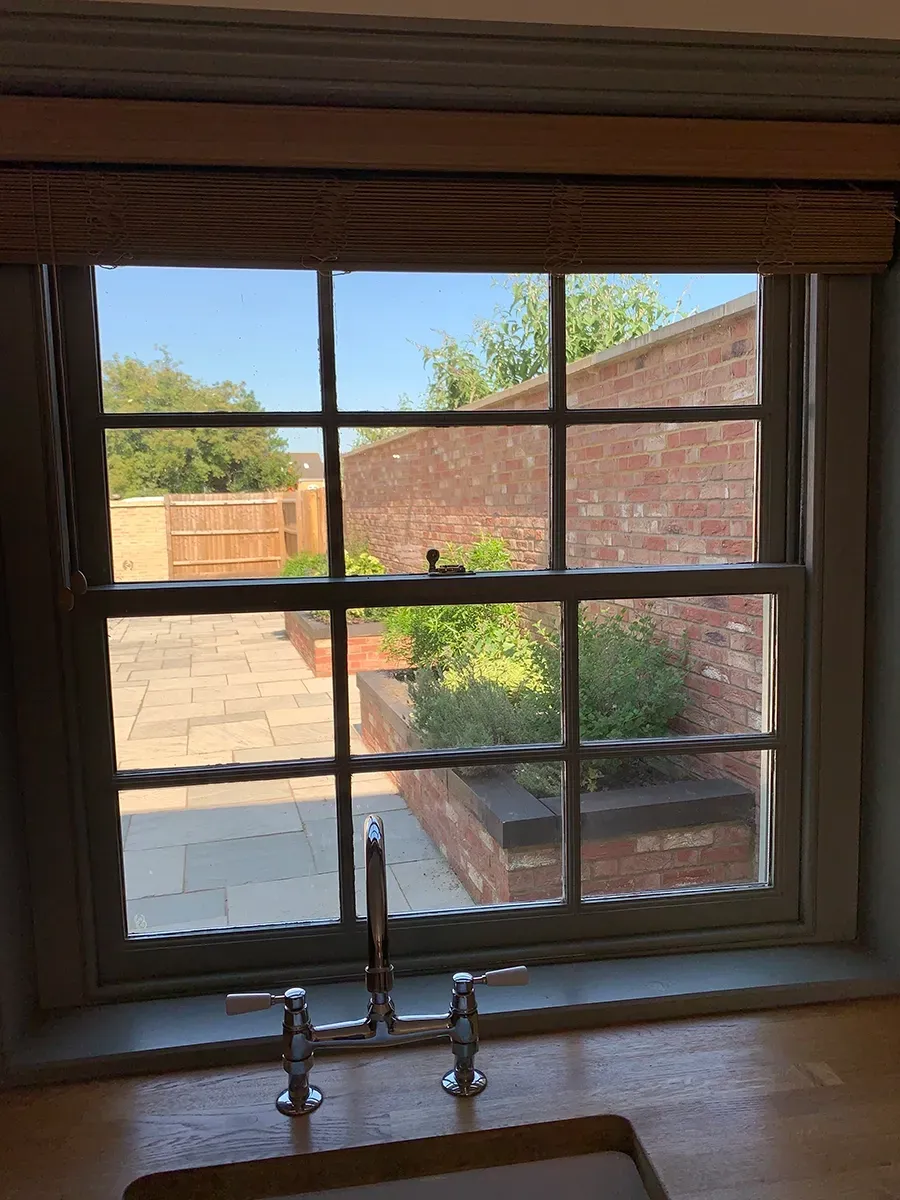 A kitchen sink is sitting under a window with a view of a brick wall.
