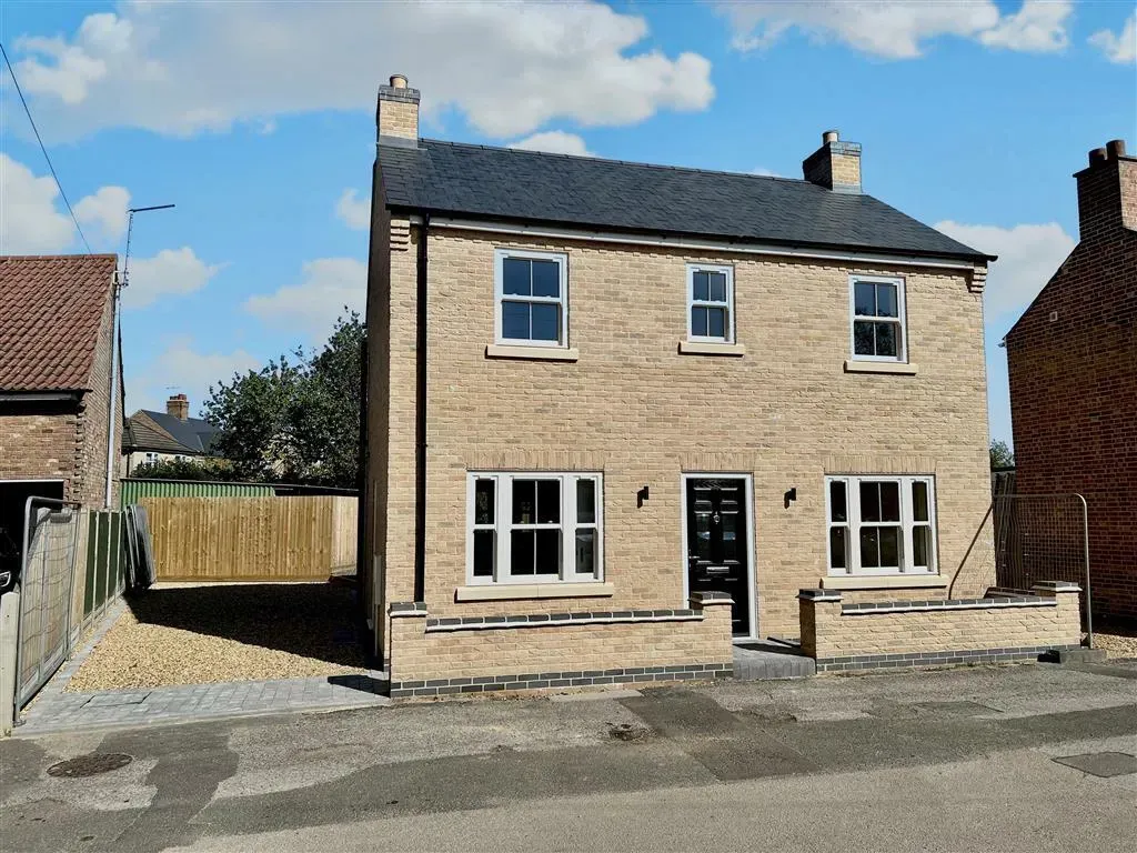 A brick house with a black roof and white windows