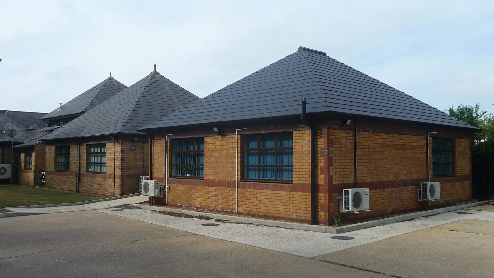 A brick building with a black roof and a lot of windows