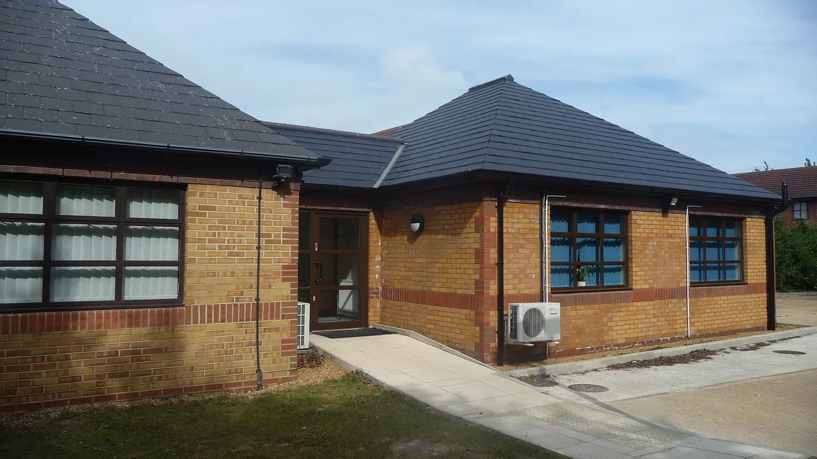A brick building with a black roof and a black air conditioner