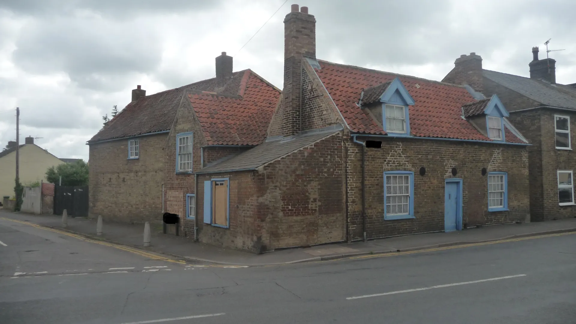A brick building with a blue door is on the corner of a street.