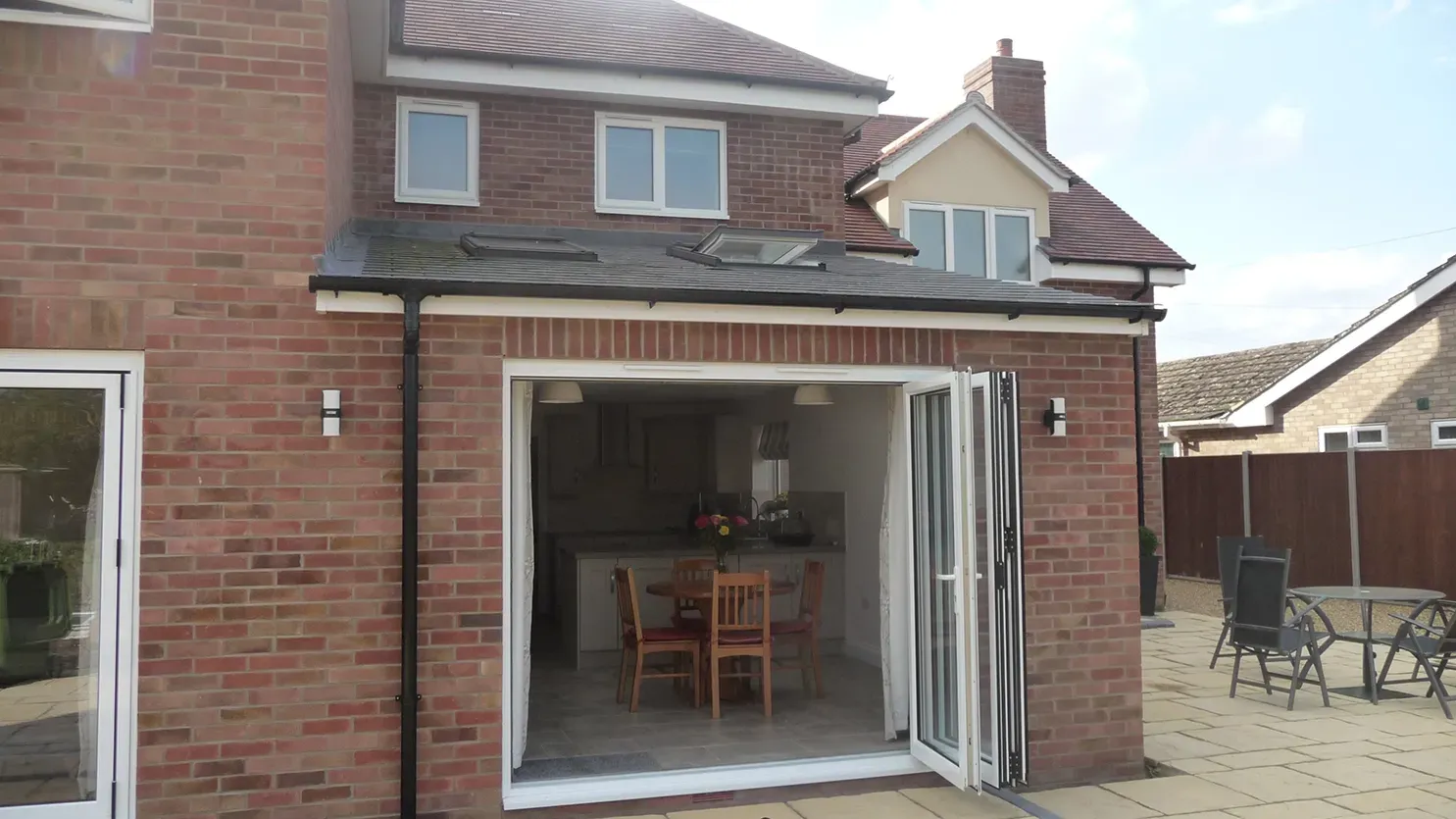 A brick house with sliding glass doors open to a patio