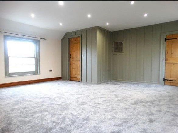 An empty room with a carpeted floor and a wooden door.
