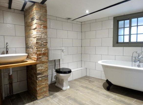 A bathroom with a tub , toilet , sink and window.