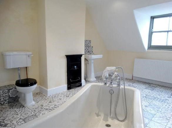 A bathroom with a bathtub , toilet , sink and fireplace.