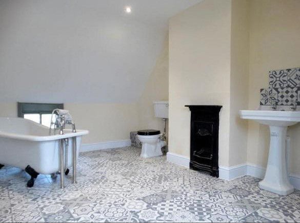 A bathroom with a bathtub , toilet , sink and fireplace.