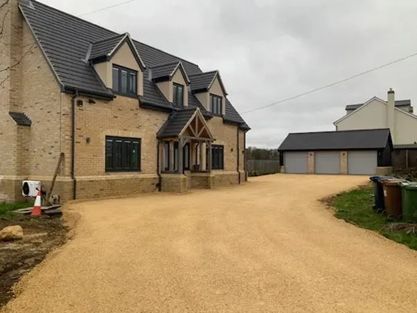 A large house with a gravel driveway in front of it.
