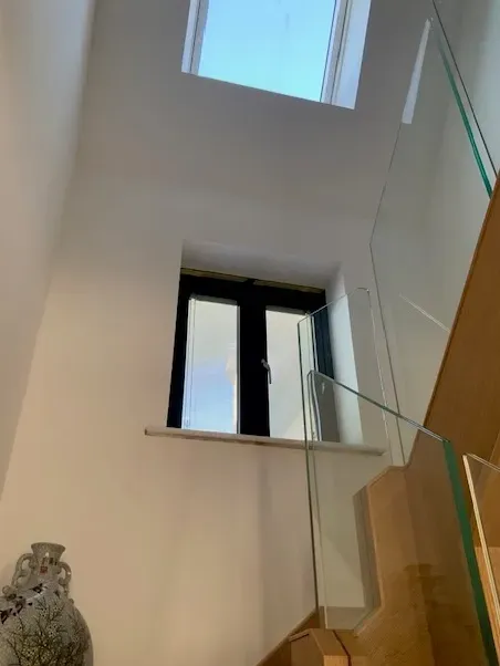 Looking up at a staircase with a window and a glass railing.