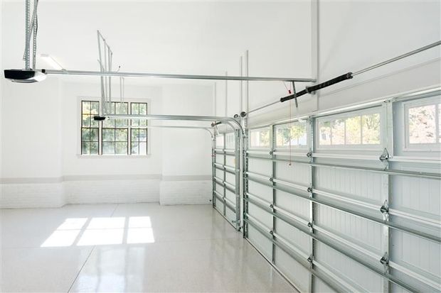 Empty, white garage interior with windows and garage door.