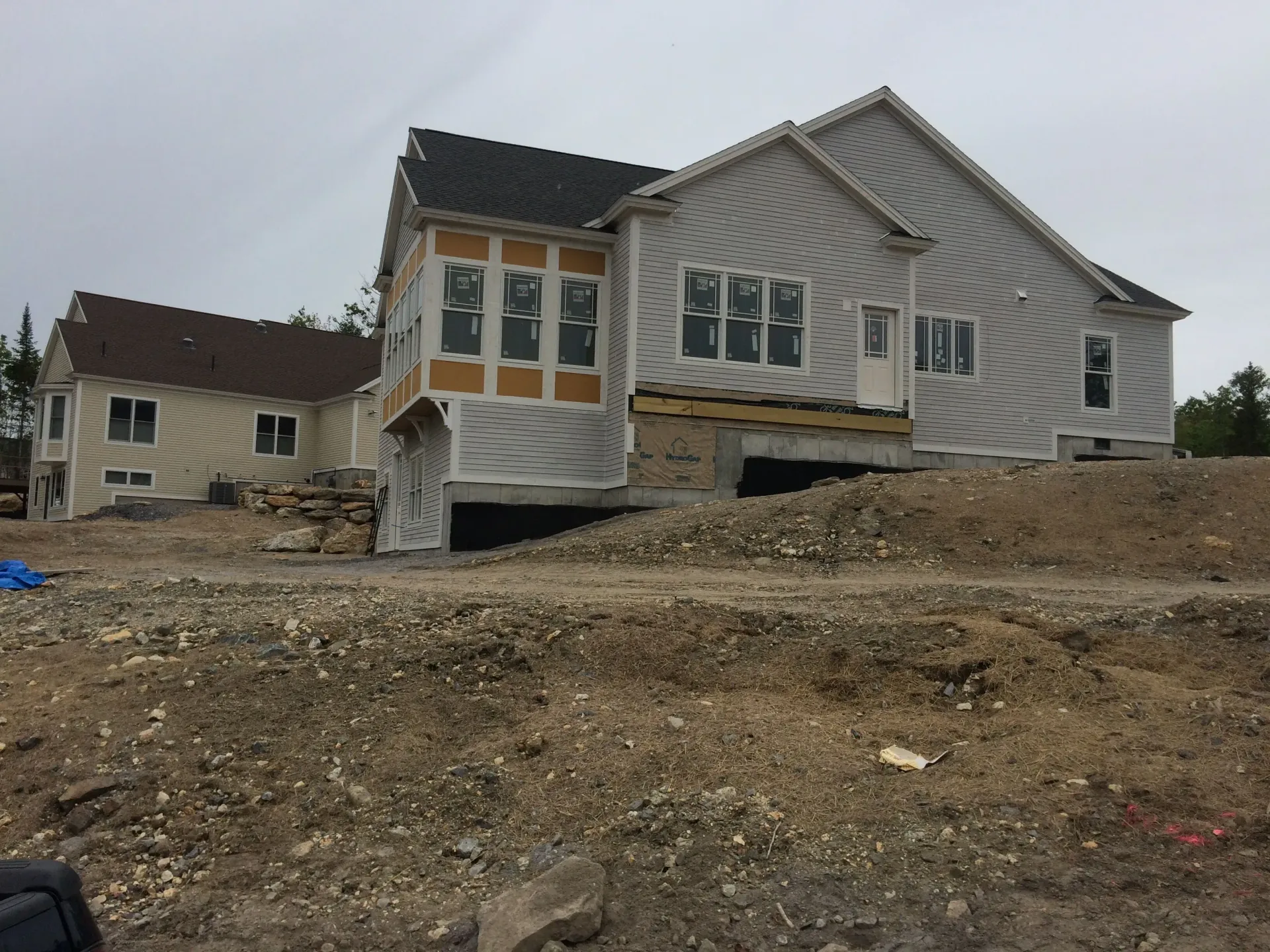 A large white house is sitting on top of a dirt hill.
