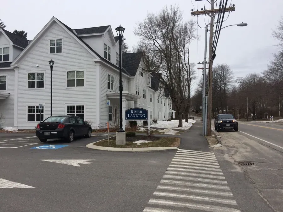A black car is parked in front of a white building