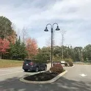 A car is parked in a parking lot next to a street light.