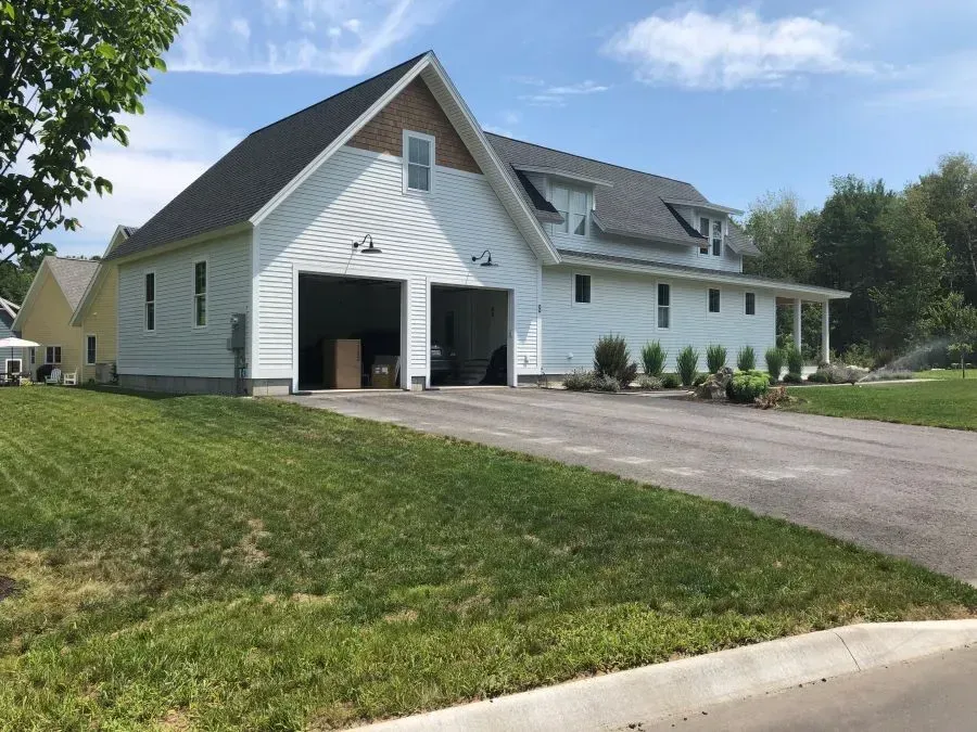 A white house with a garage and a driveway in front of it.