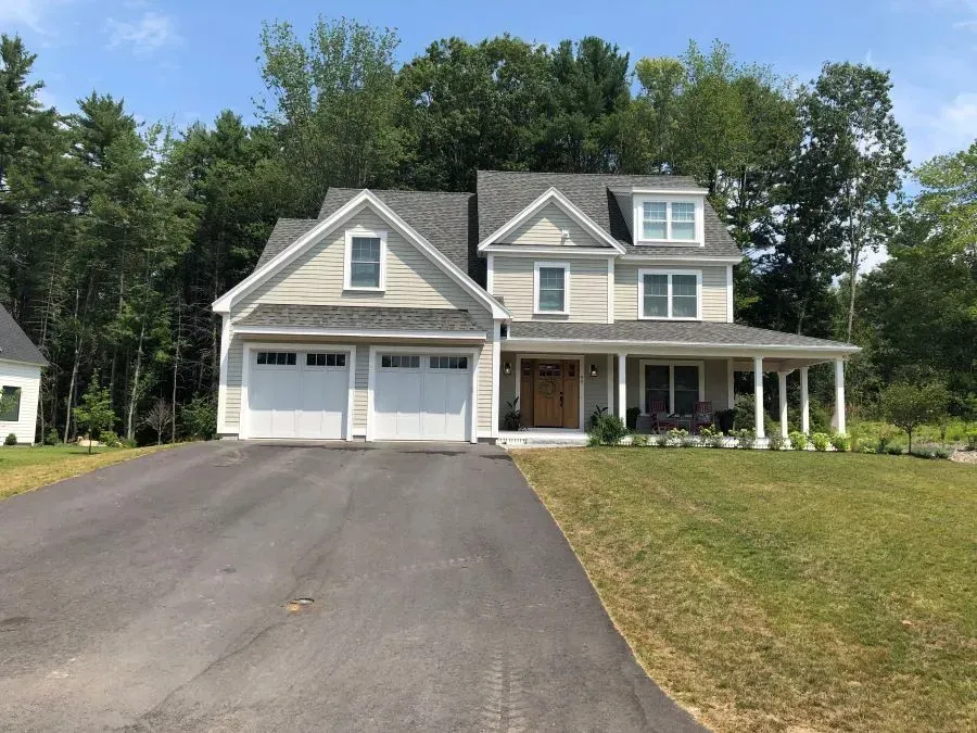 A large house with a driveway leading to it is surrounded by trees.