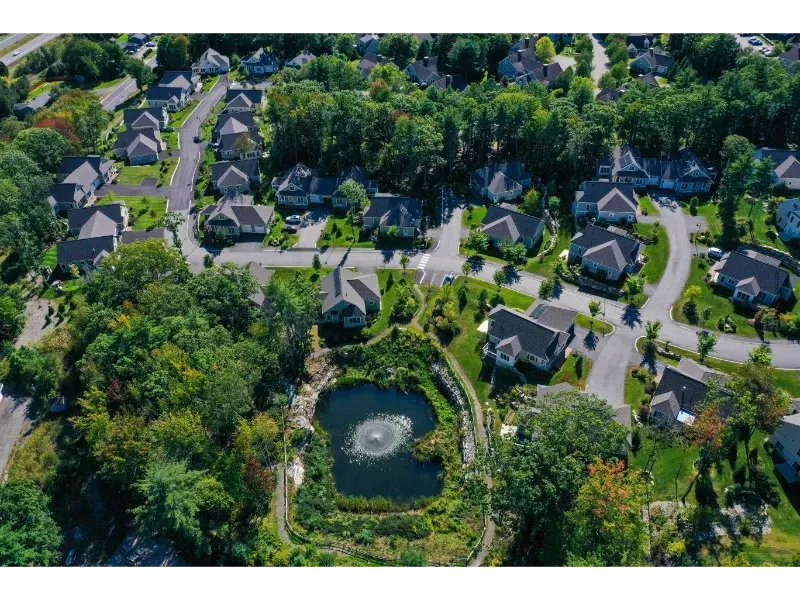 An aerial view of a residential neighborhood with a pond in the middle