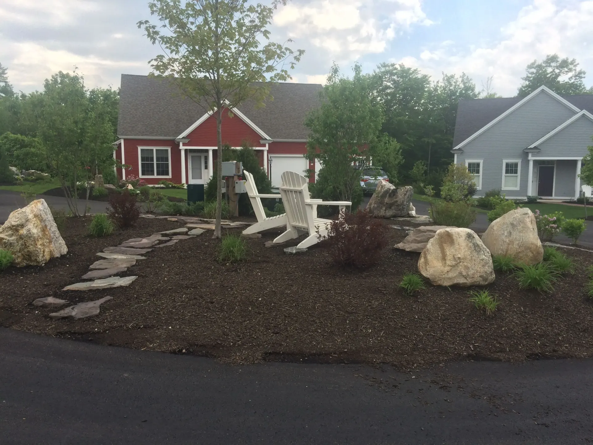 A red house is sitting next to a gray house in a residential area.