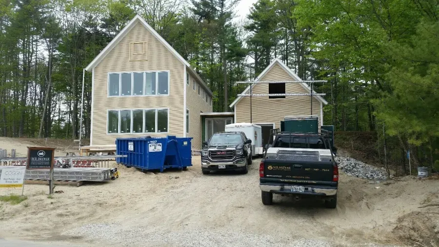 Two trucks are parked in front of a house under construction.