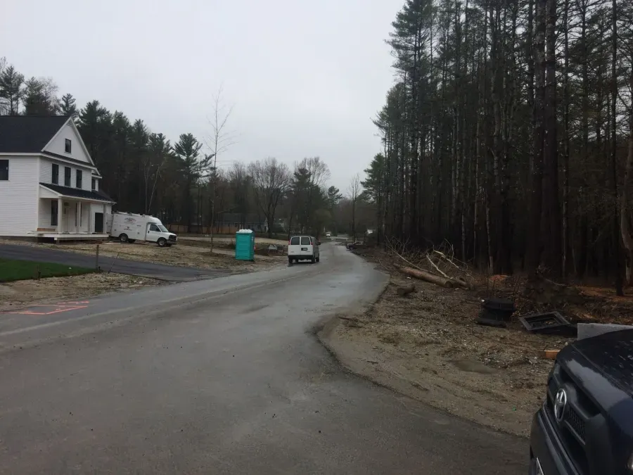 A car is parked on the side of a road next to a house under construction.