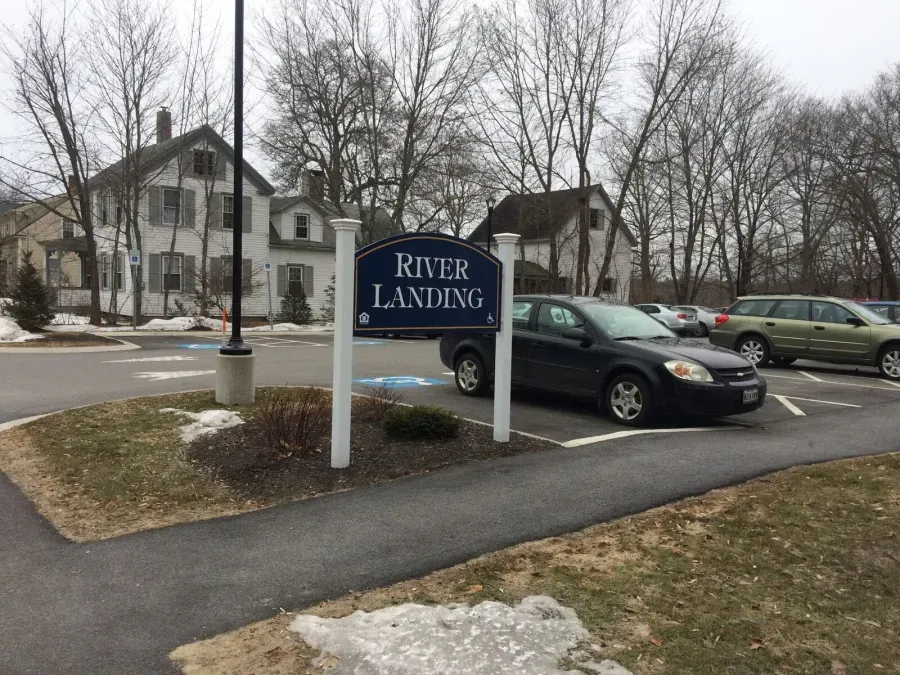 A river landing sign is in front of a parking lot