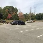 A parking lot with cars parked in it and trees in the background.