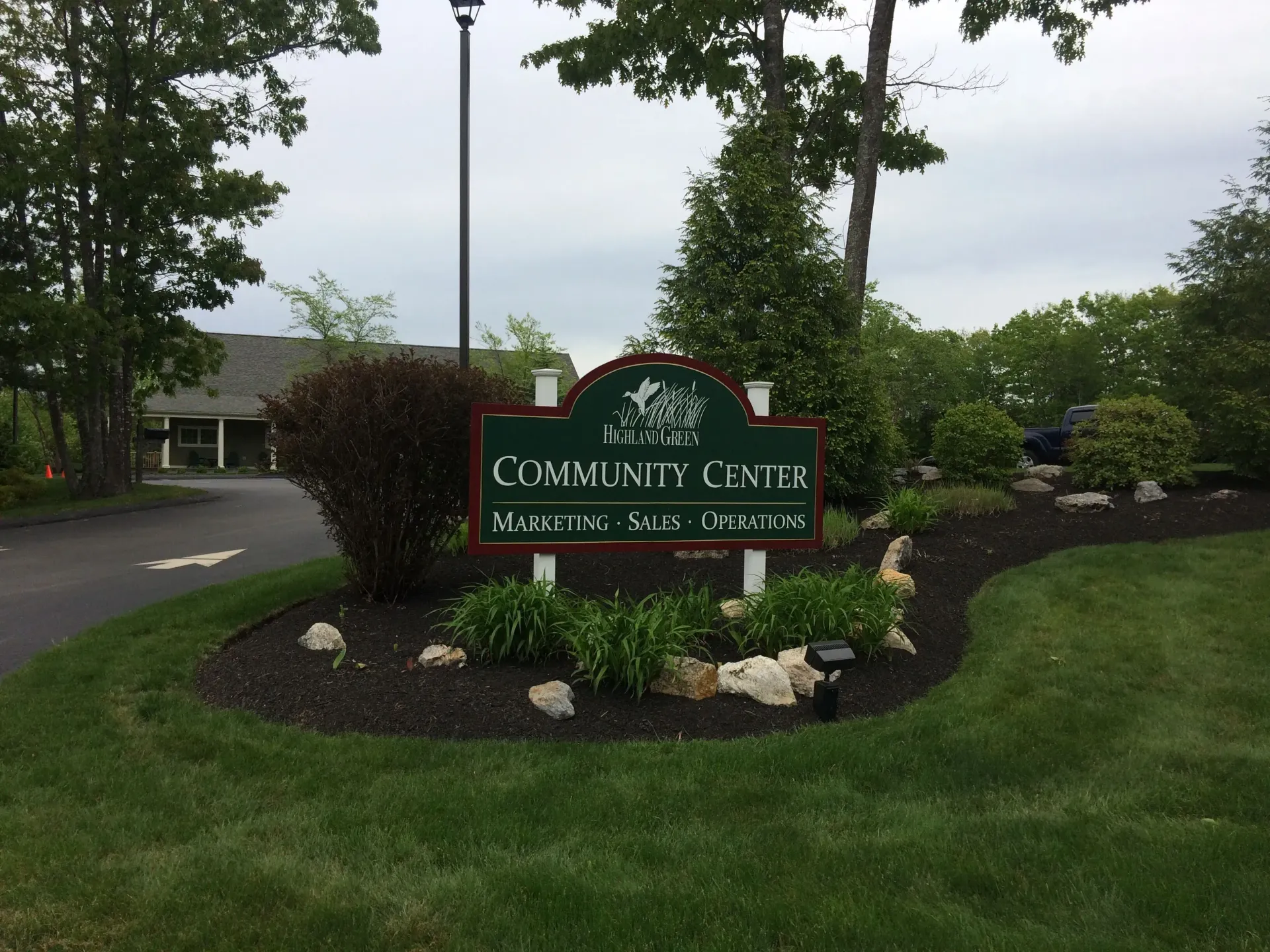 A community center sign is surrounded by grass and trees
