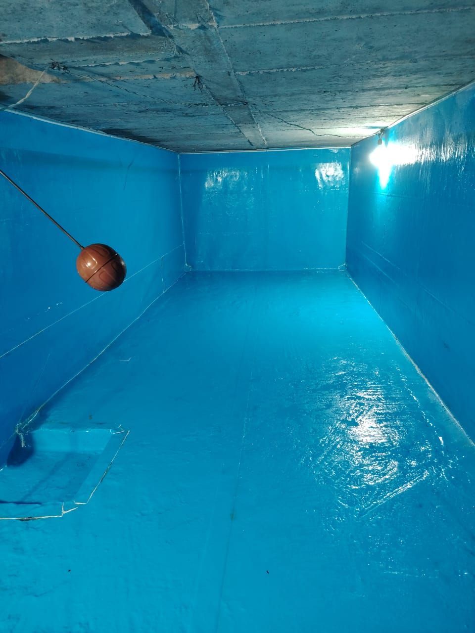 Tobogán acuático azul interior con una pelota de baloncesto flotando cerca de la pared izquierda.