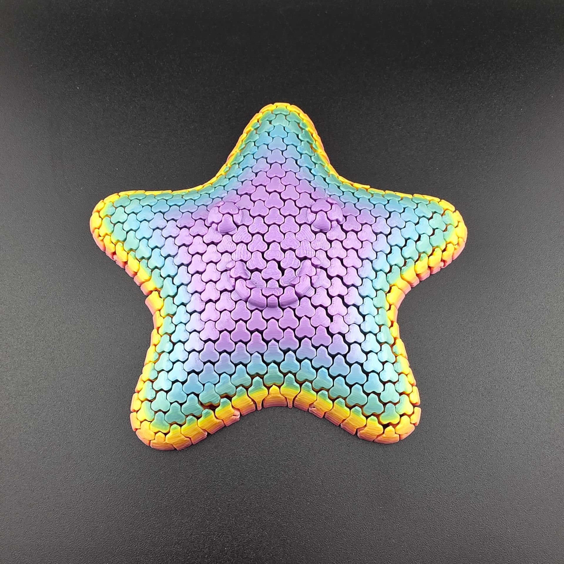 Colorful starfish toy with textured surface, rainbow hues, and orange trim.