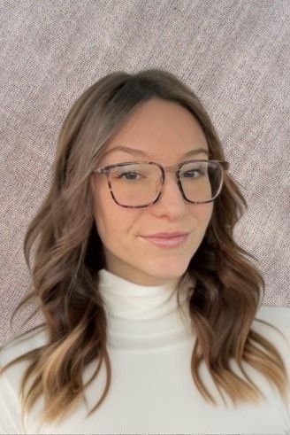 Woman with brown hair and glasses, wearing a white turtleneck.