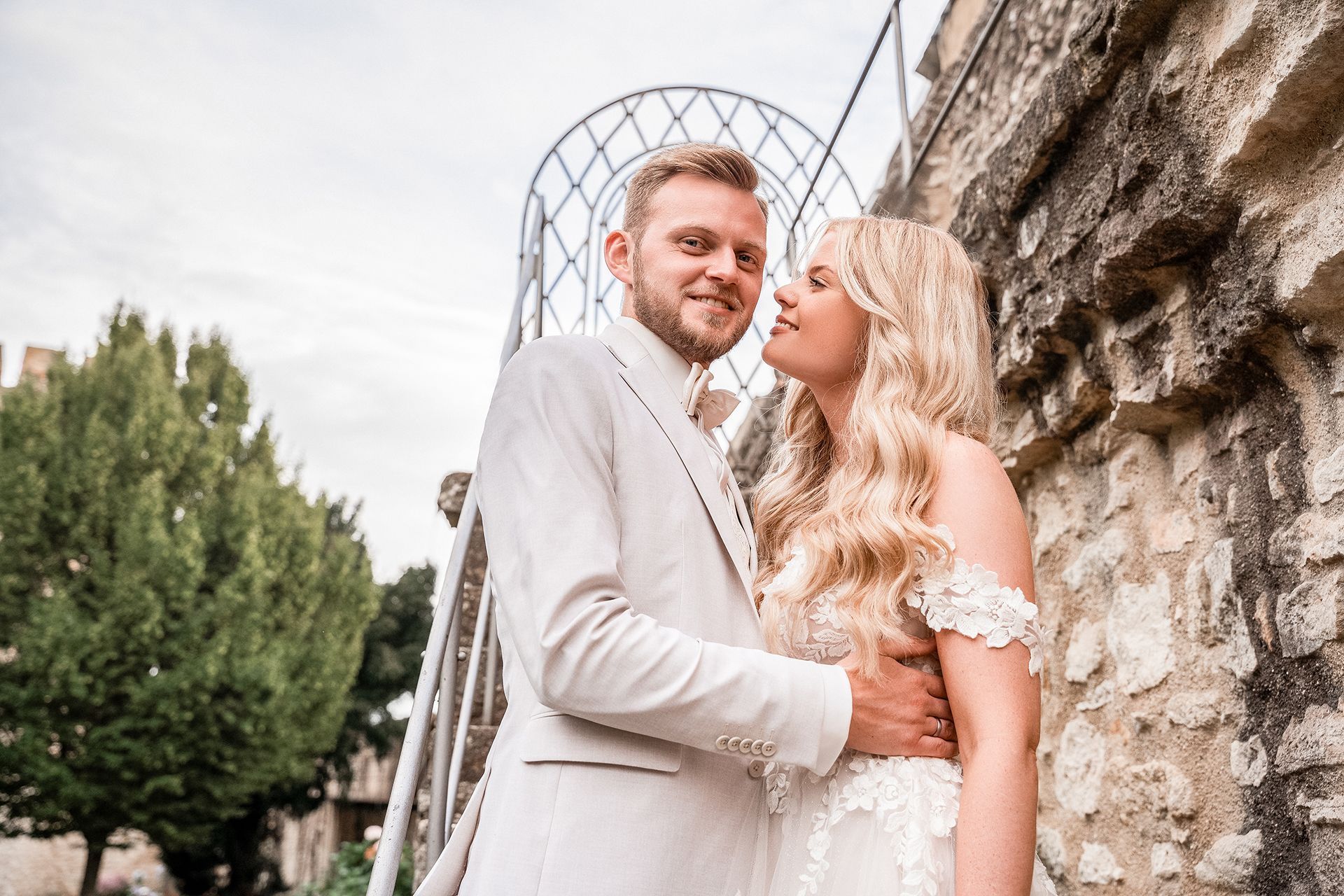 Brautpaar vor historischen Mauern Ingelheims, er lächelt in die Kamera, sie schaut glücklich